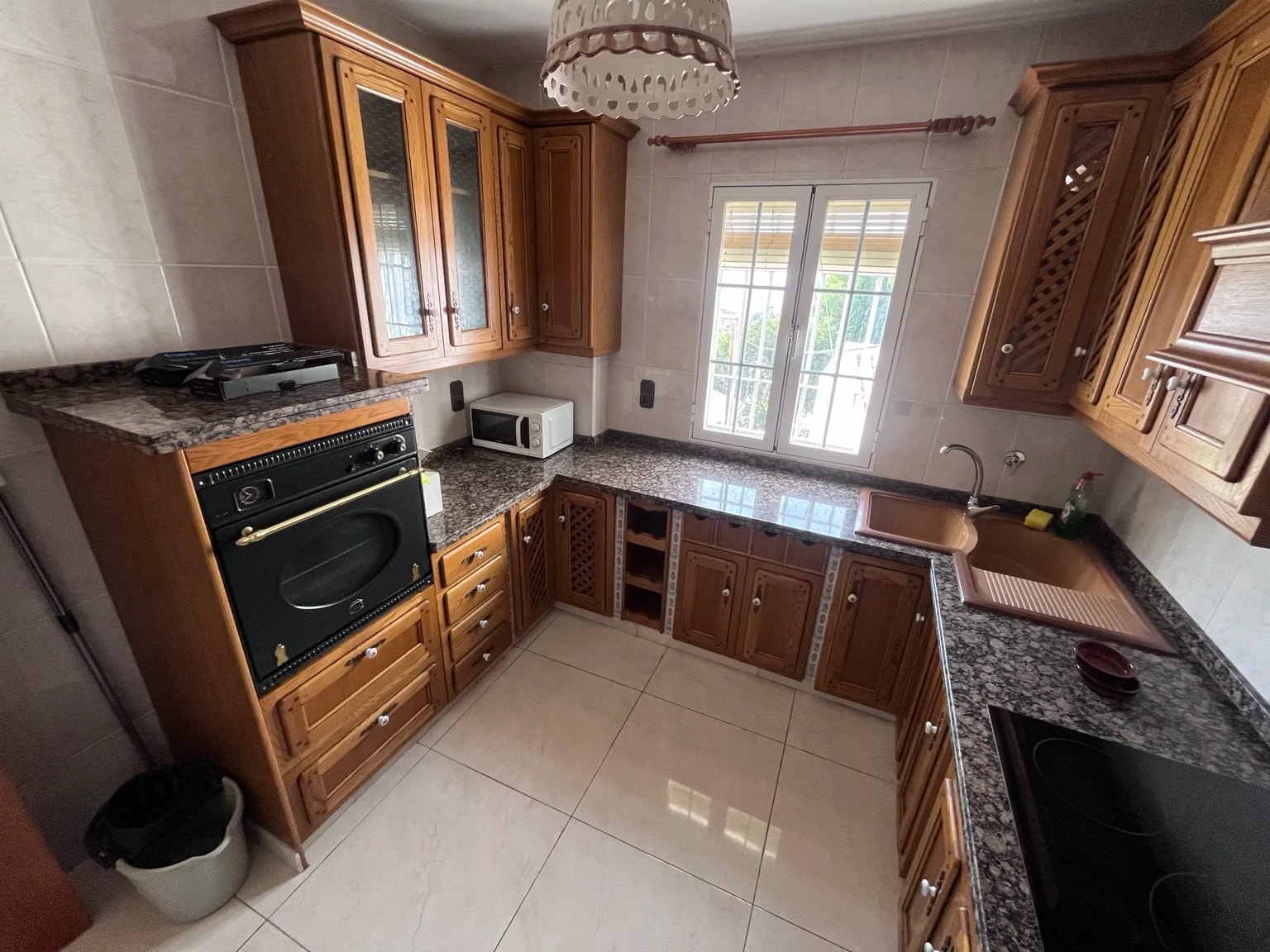 Cocina de la casa con muebles de madera, horno y encimera junto a la ventana.