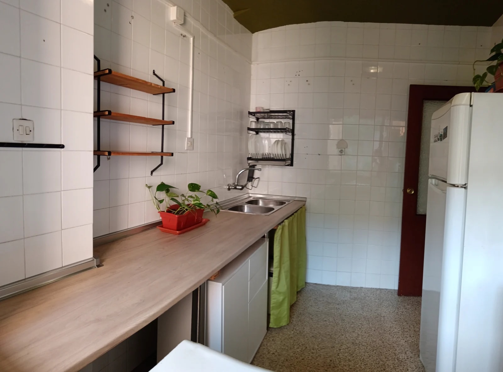 Cocina del piso con encimera de madera, fregadero y frigorífico.